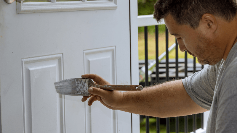 man painting front door white